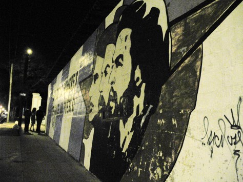 Some campaneros stroll past a propoganda mural of Che Guevara, Fidel Castro and 