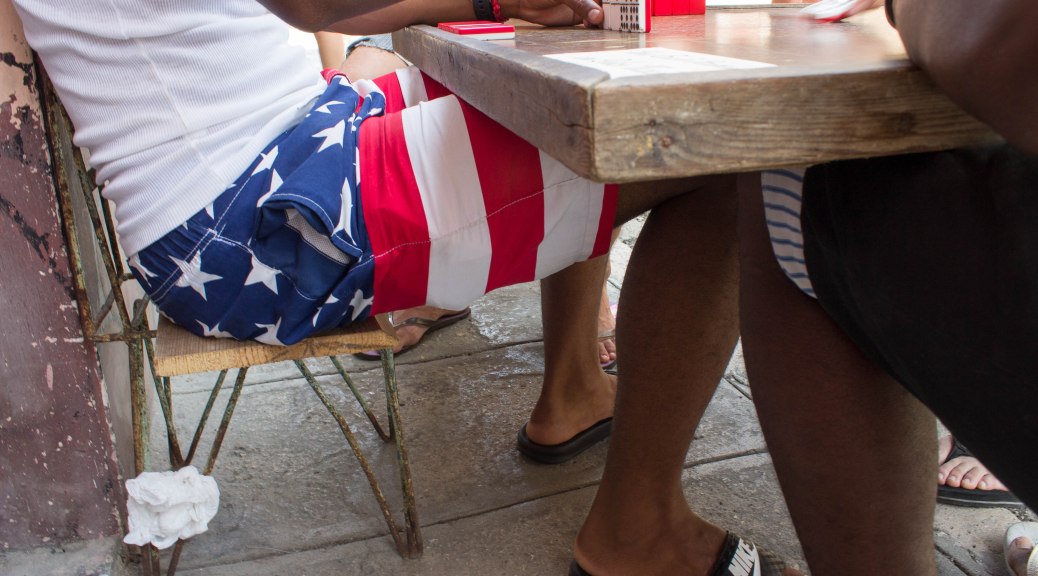 Cuban with American flag bathing suit in Havana plays dominoes